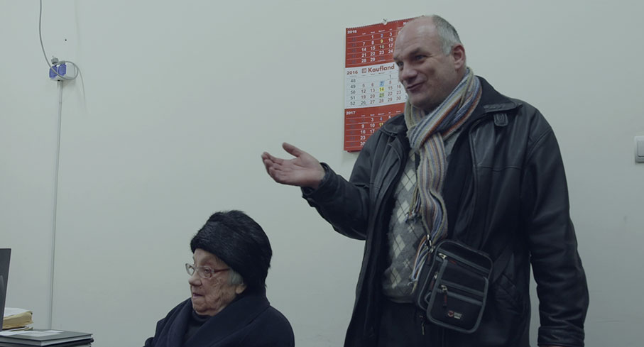 An elderly woman and her younger male friend crash the interview to talk to Laurentiu about a land rights issue.