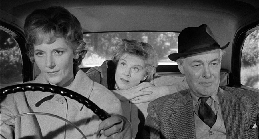 Flora defends Norman from the back seat as Evelyn badmouths him while her husband Harold listens 