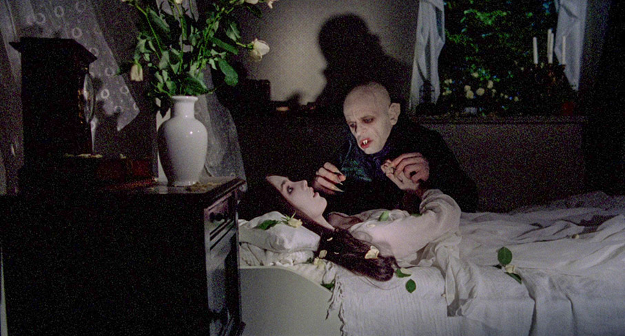 Lucy darws Dracula to her bed as dawn approached